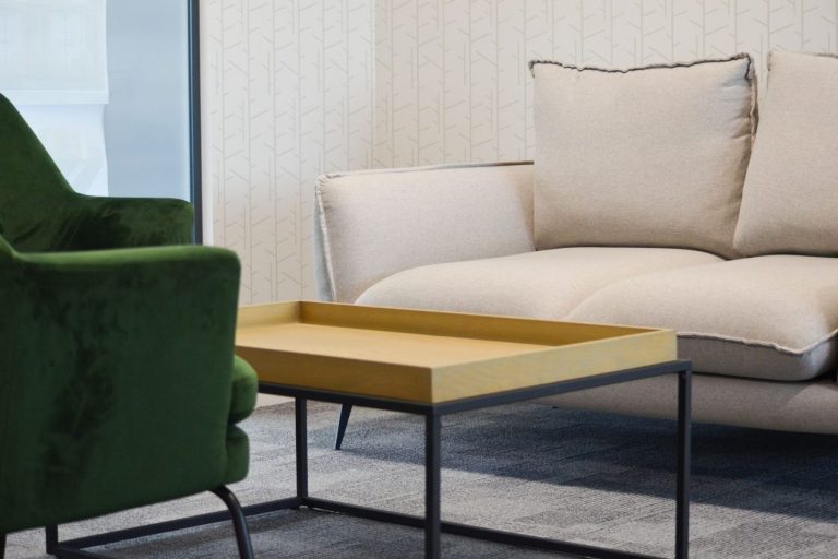 Contemporary lounge seating with upholstered sofa, green armchair and brass coffee table.