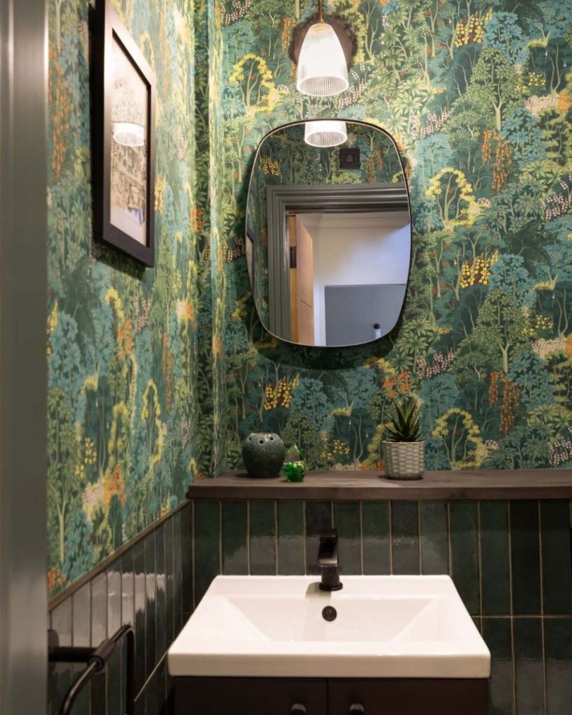 Contemporary bathroom in Guildford featuring botanical wallpaper, dark green tiles, modern vanity unit, and oval mirror with pendant lighting.