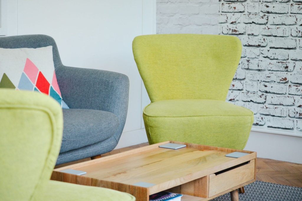 Modern breakout space seating with upholstered chairs, wooden coffee table, and textured feature wall.