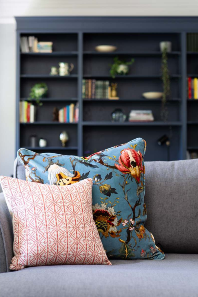Contemporary lounge seating with patterned cushions set against bespoke blue shelving.